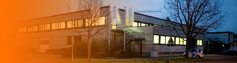 Elektro Adelmann Gebäude bei Nacht Das Firmengebäude von Elektro Adelmann in der Dämmerung, beleuchtet mit großen Fenstern und klarer Sicht auf die Umgebung.